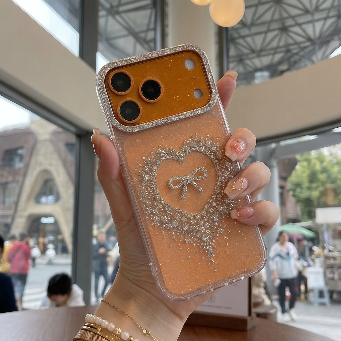 Person holding a phone case with a heart design in a cafe setting